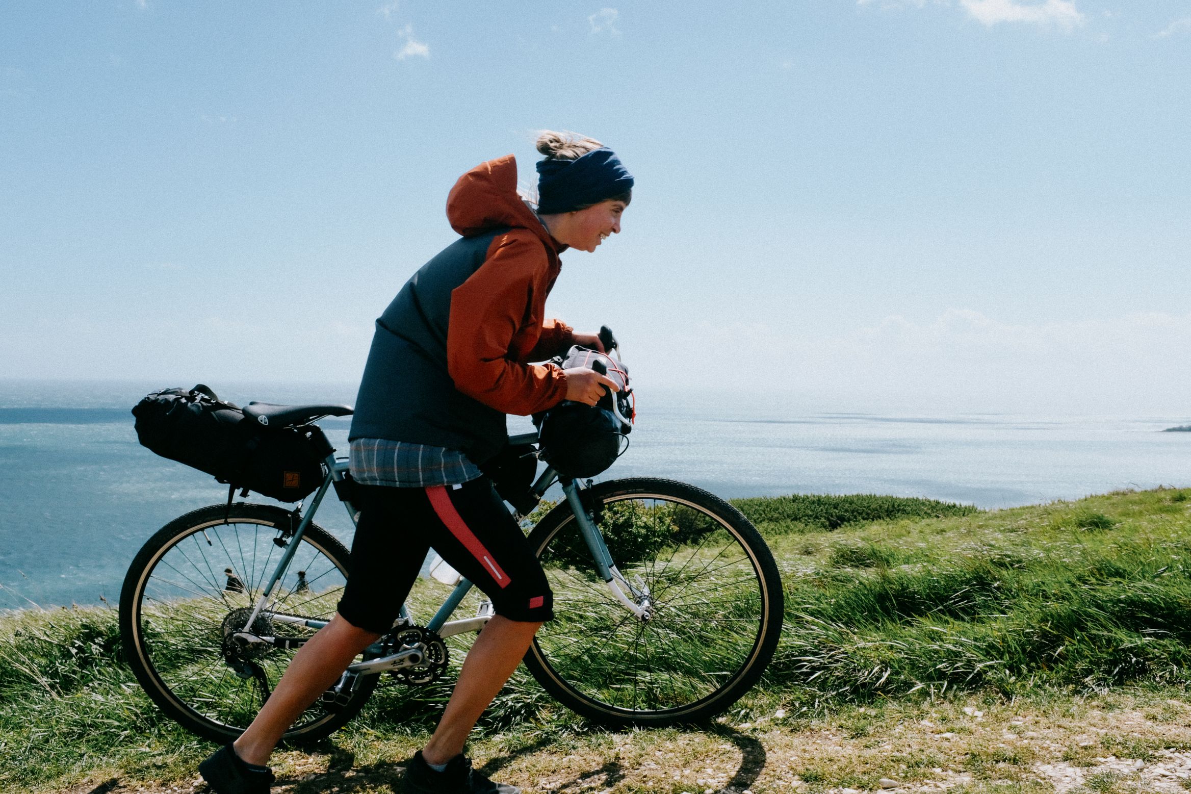 Pushing the loaded bike along the clifftop, sea flat behind