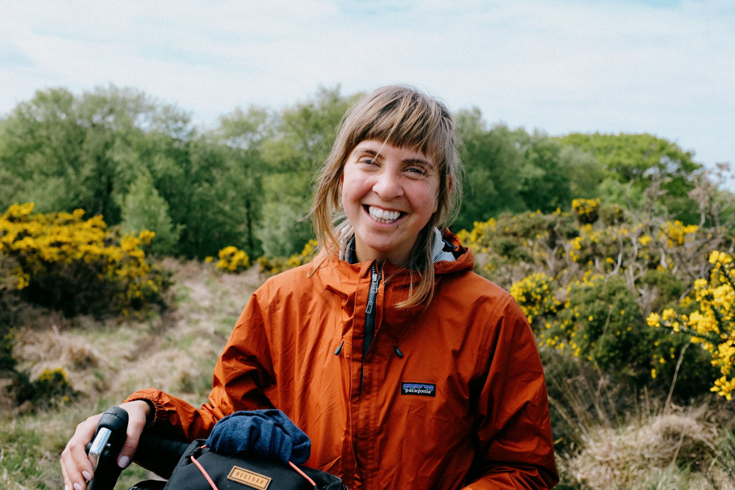 Laughing, helmet off, gorse and scrub behind