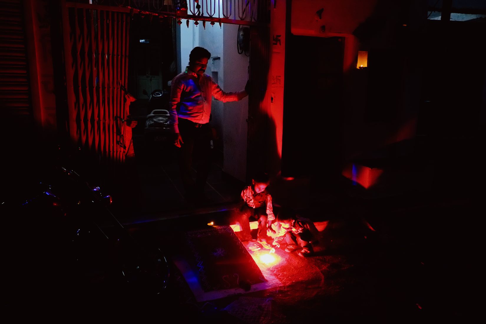 A man stepping back from fireworks burning on the ground, the whole frame lit red