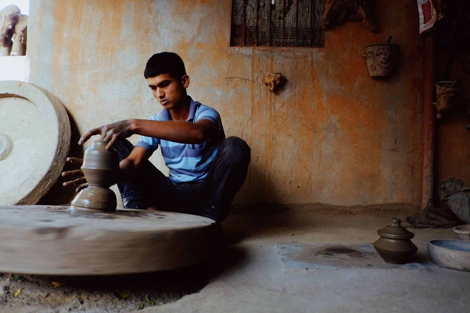 The wheel spinning to a blur while he leans in and draws the clay up