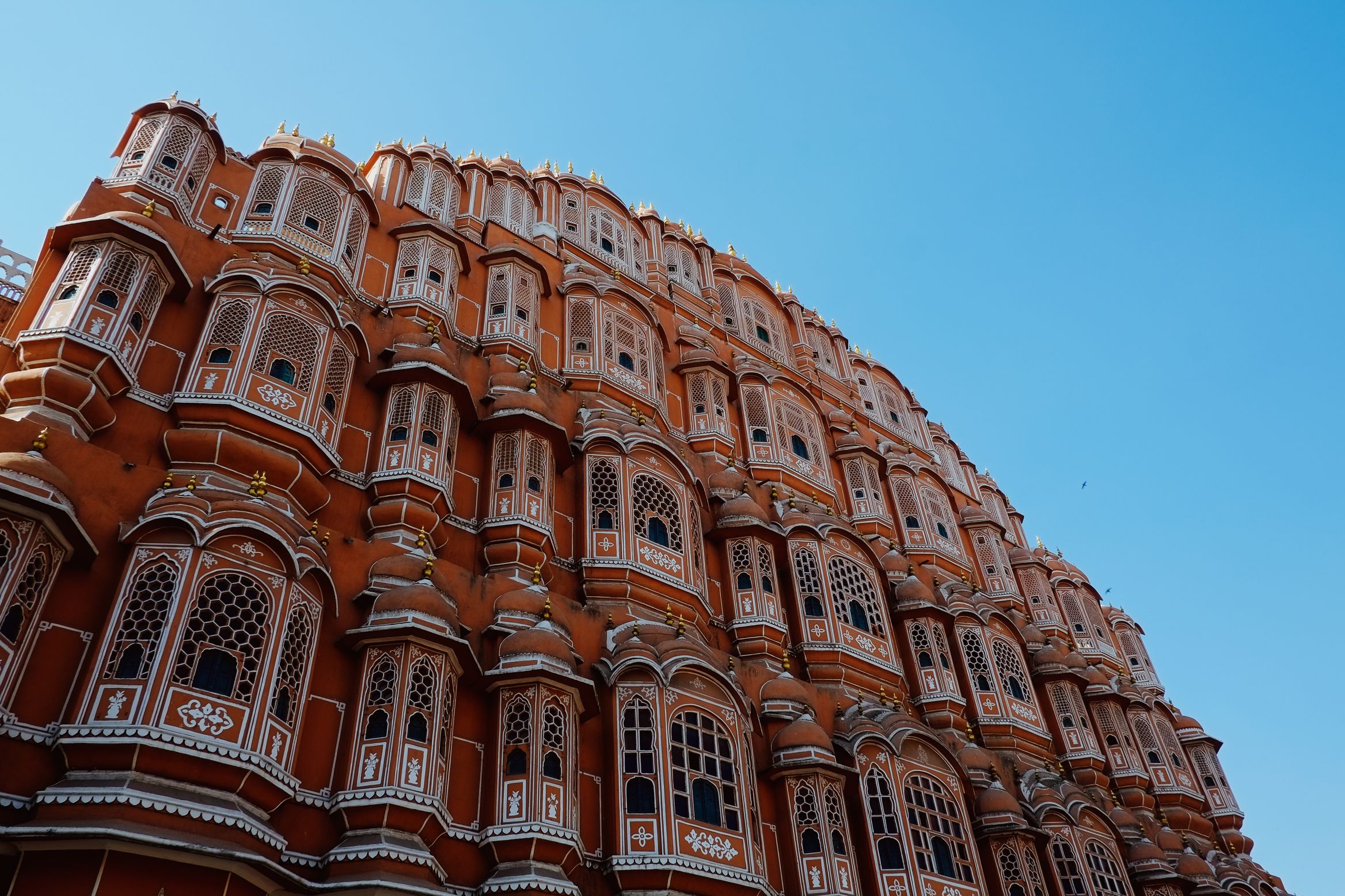 The Hawa Mahal from below, its honeycomb of small windows curving up into a cloudless sky