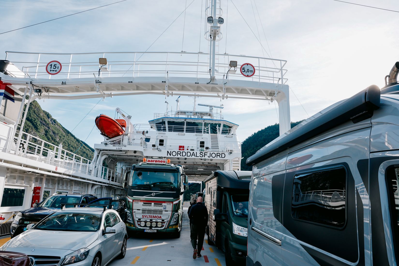 The car deck of the ferry Norddalsfjord, a man walking between parked lorries and camper vans