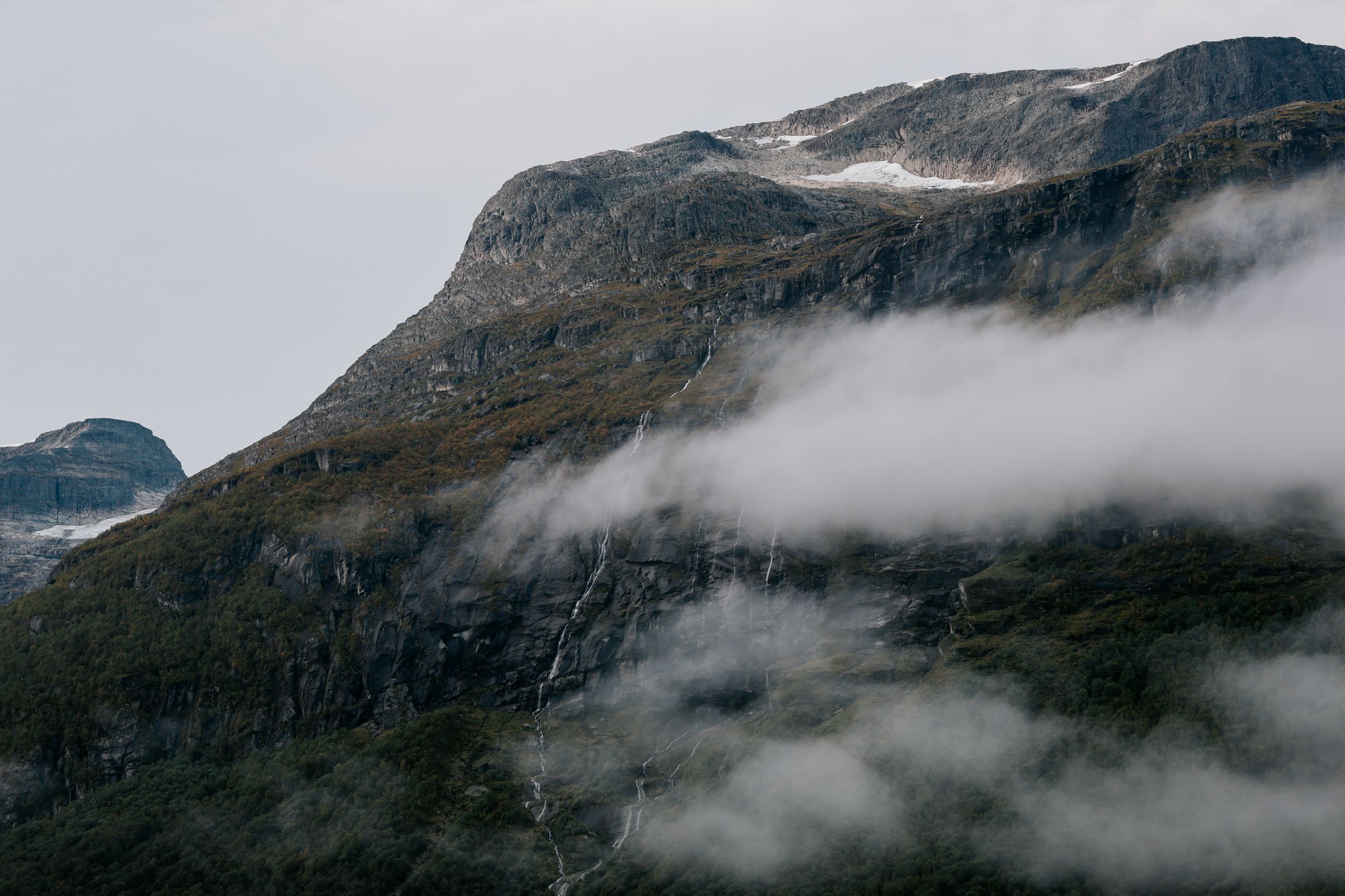 A band of cloud drifting across a snow-topped mountainside in early morning light
