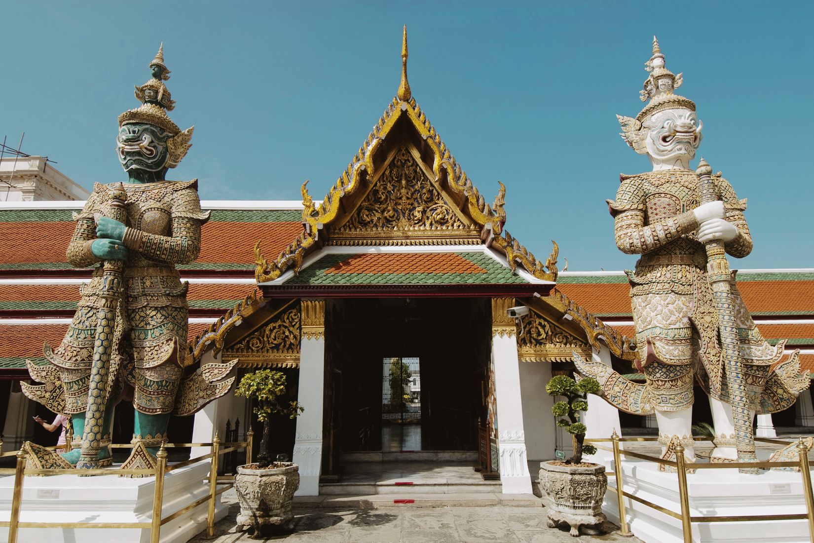 Two giant guardian figures flanking the open doorway of a temple pavilion