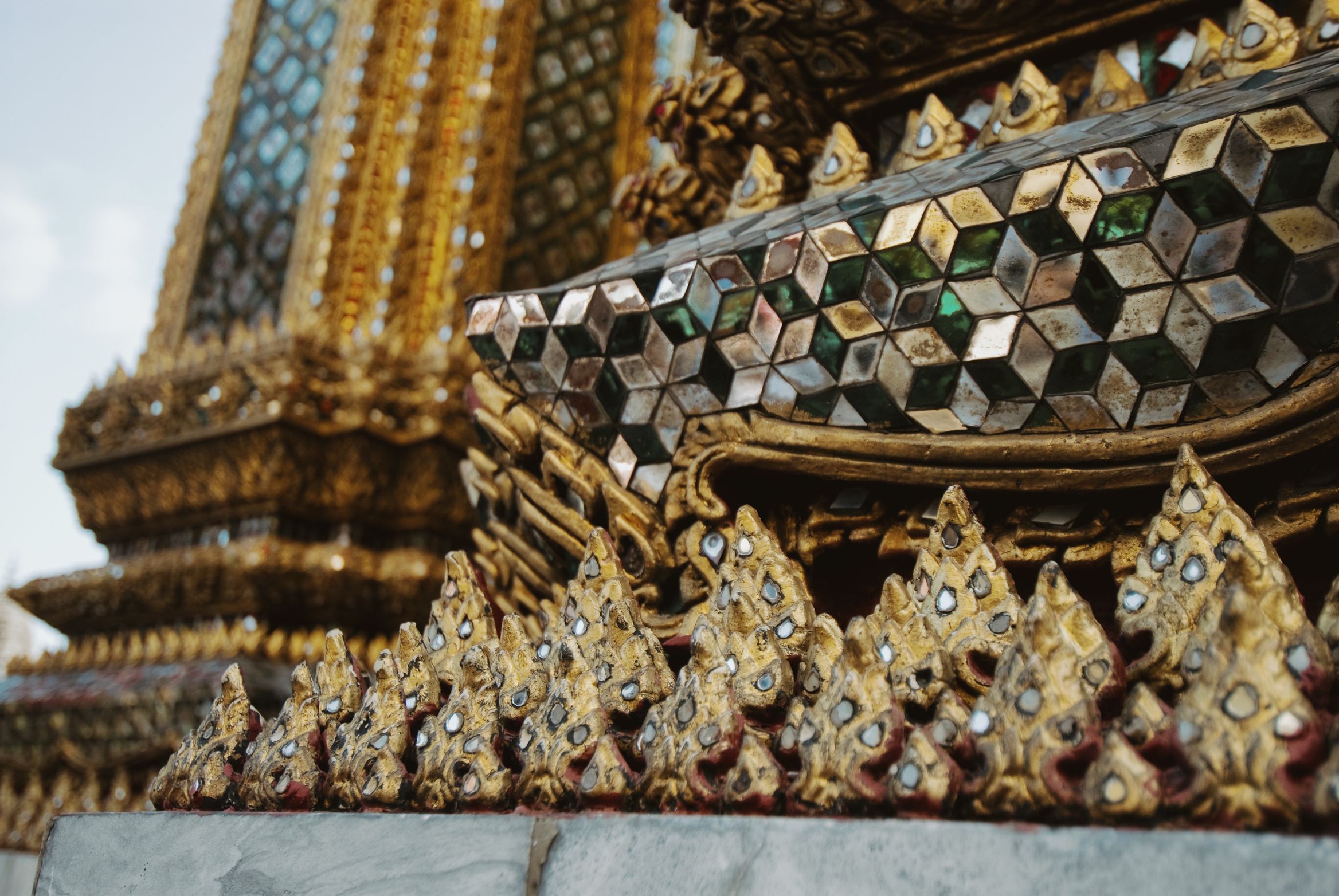 Close on mirrored glass mosaic and gilded flame ornaments on a temple base