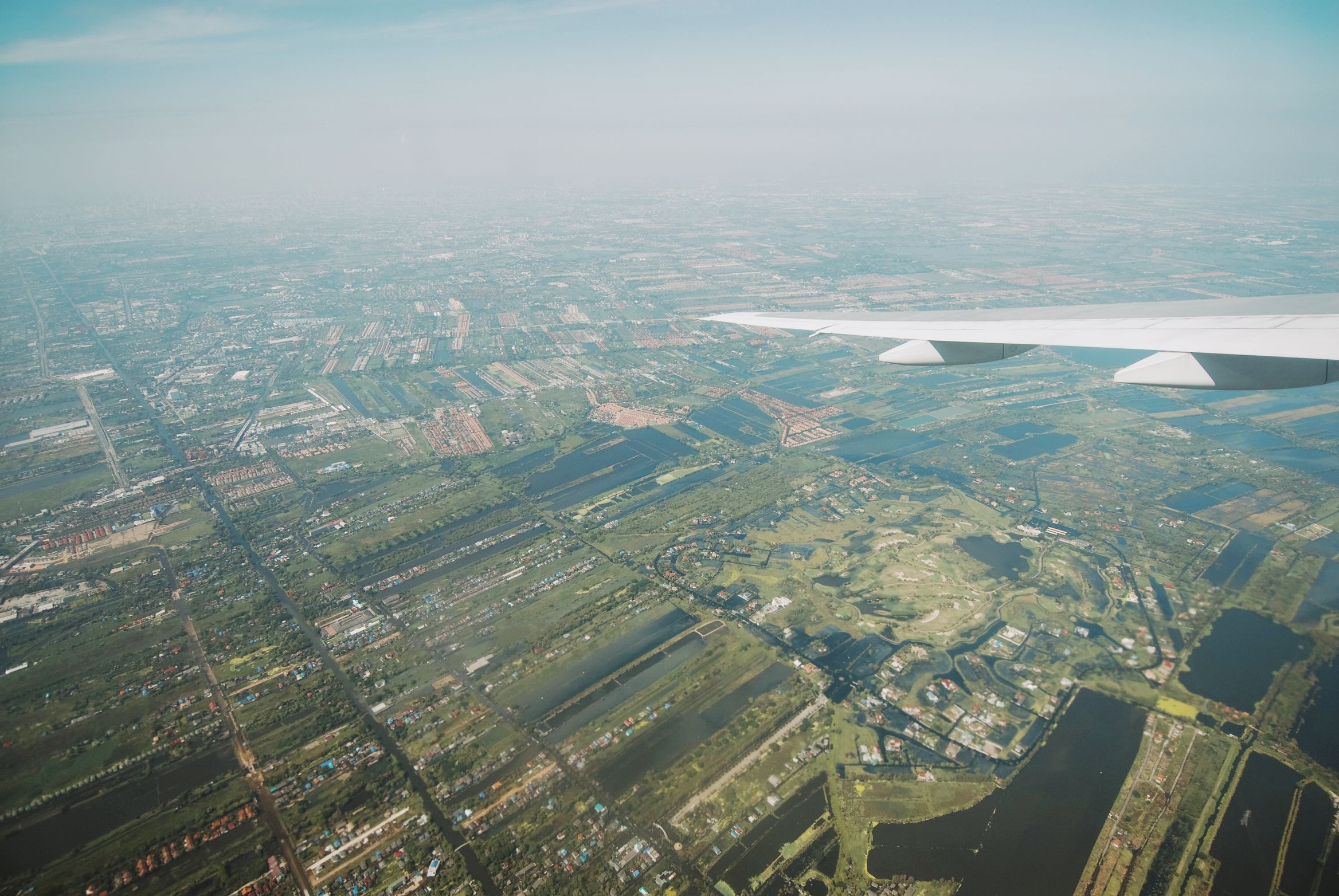 The city and its waterways seen from a plane window just after take-off, wing across the frame