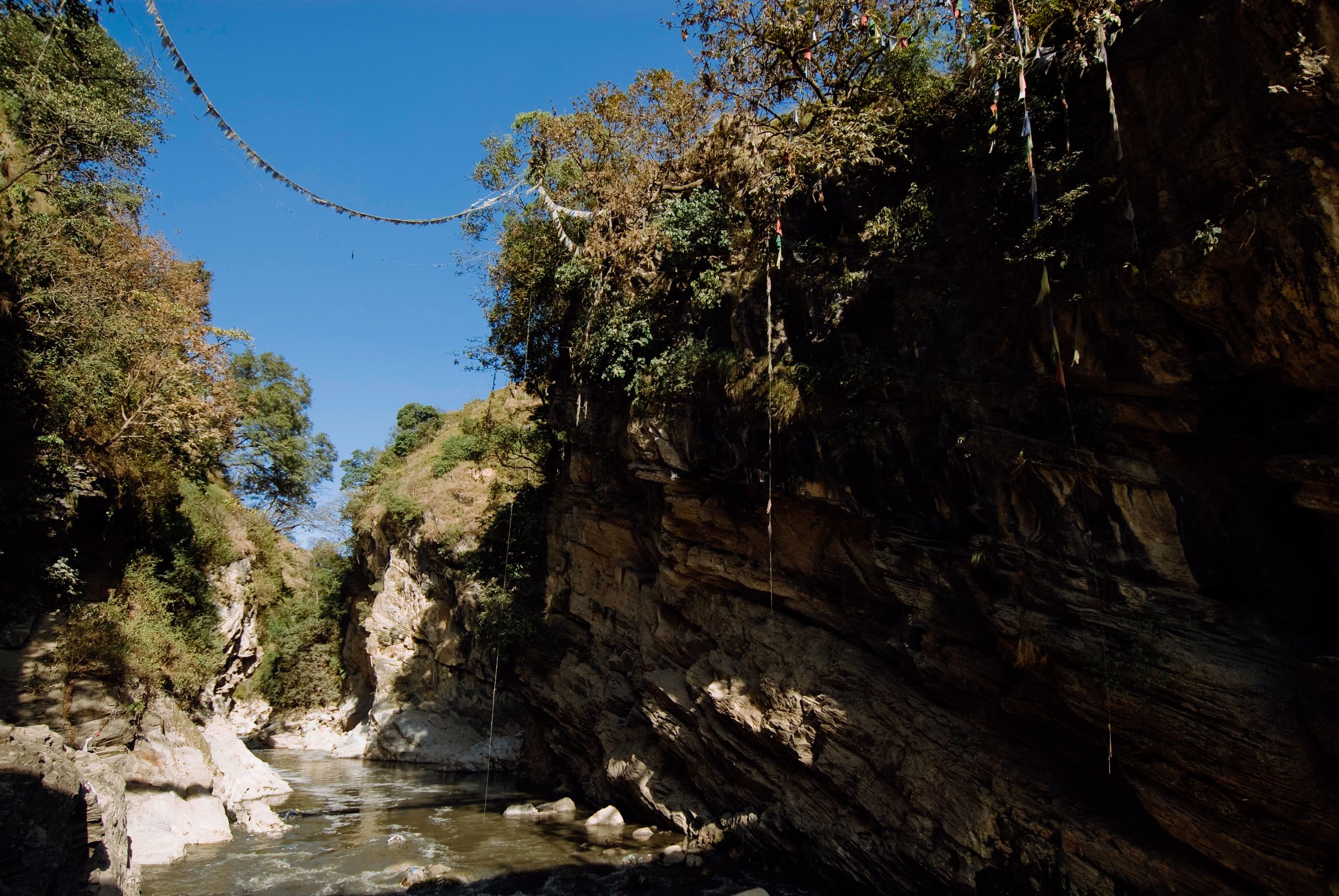 Prayer flags strung across a narrow rock gorge above the river