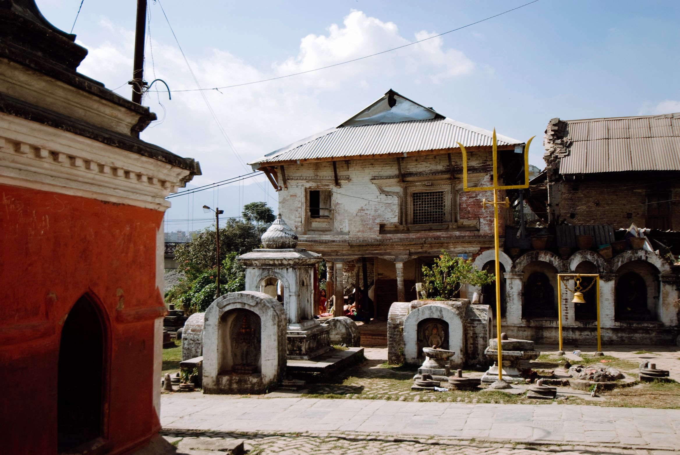 A whitewashed building with a tin roof standing over a yard of small stone shrines