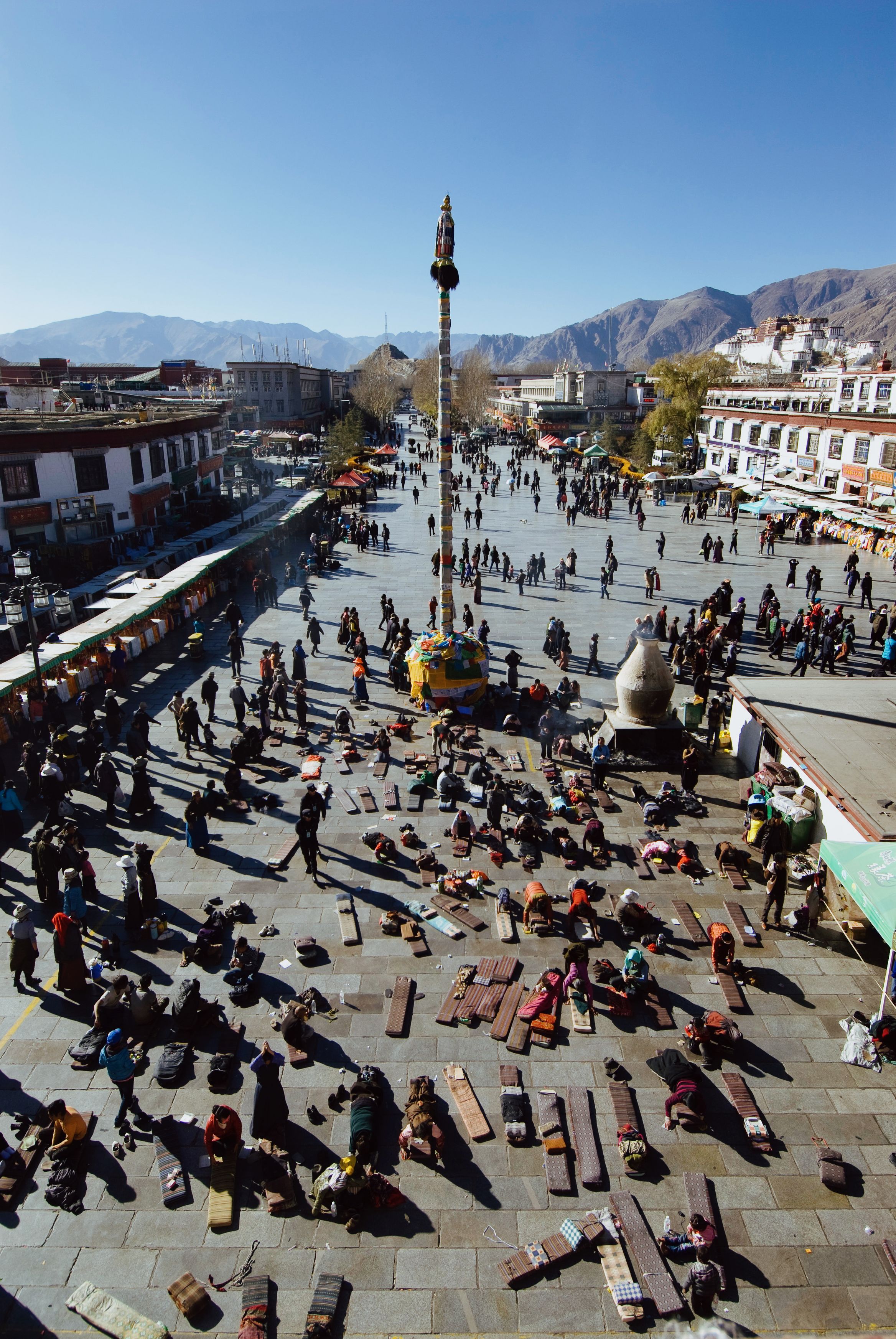 Looking down on the square from the temple roof, people prostrating on boards across the flagstones