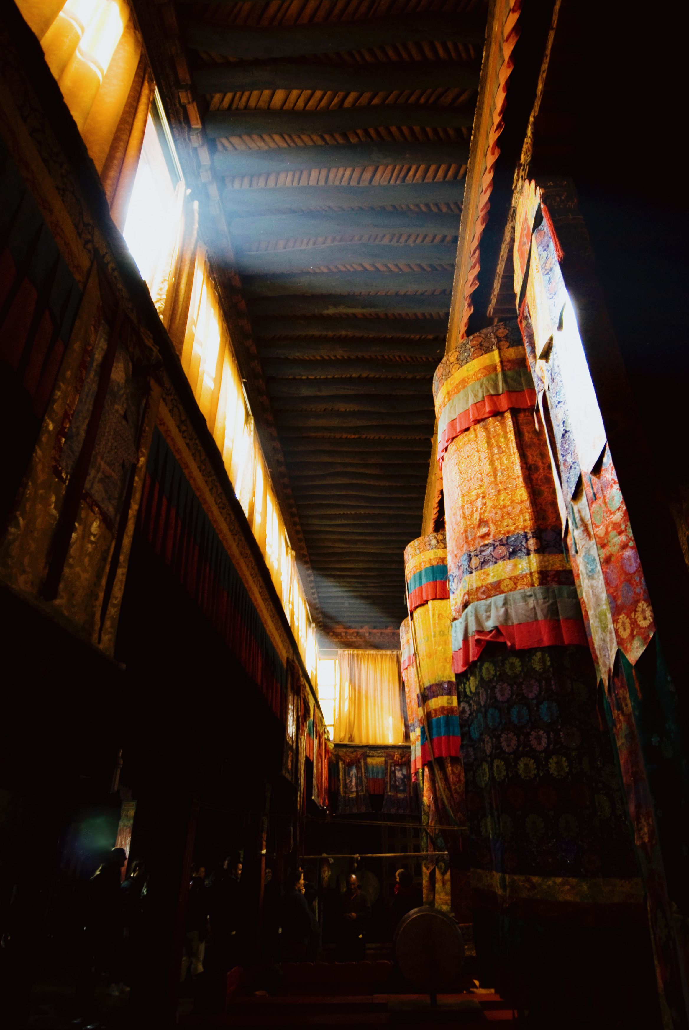 A dark assembly hall with banners hanging from the beams, light coming in along a clerestory