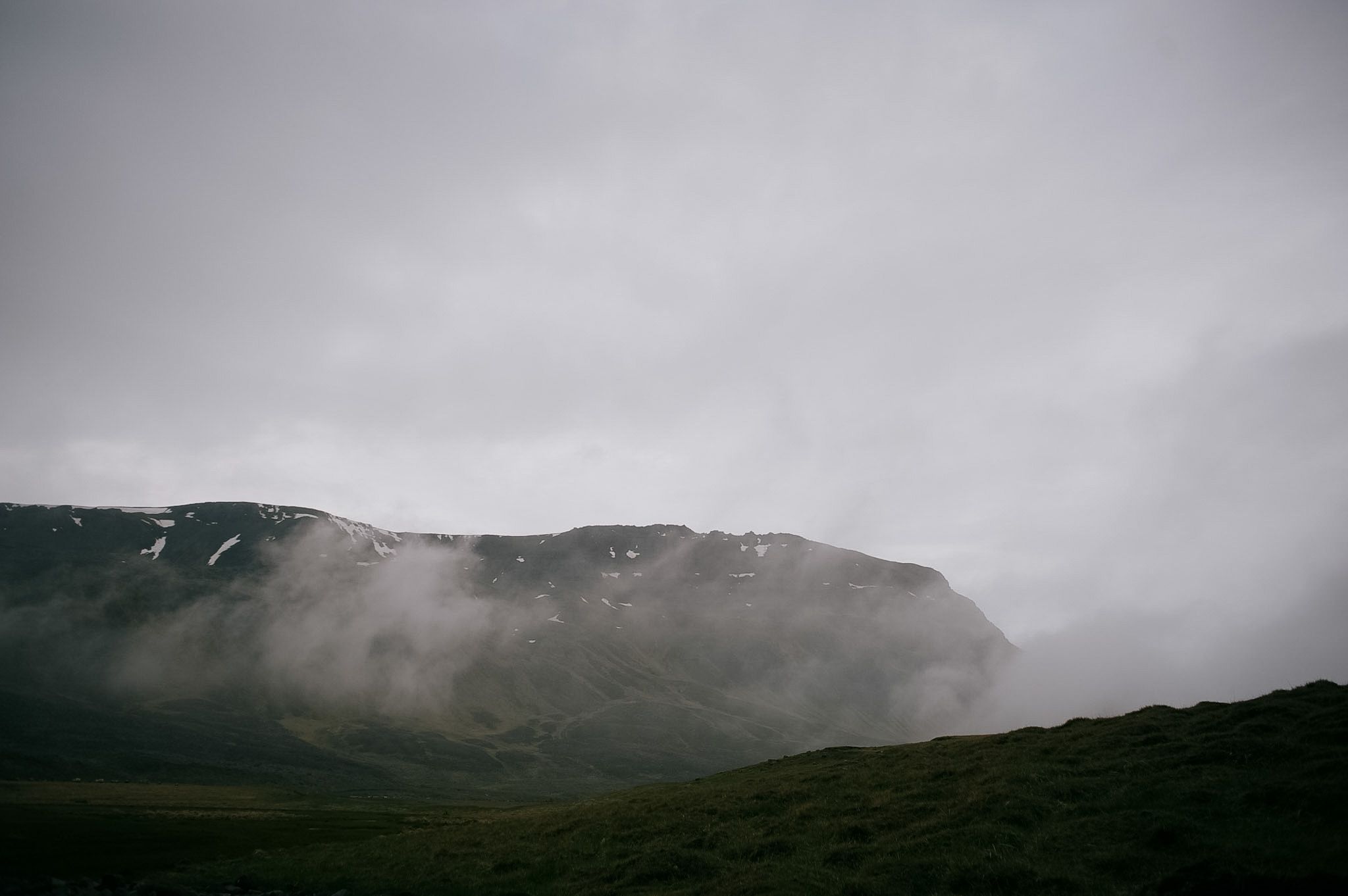 Cloud tearing across the face of a snow-streaked ridge, the moor below it almost black