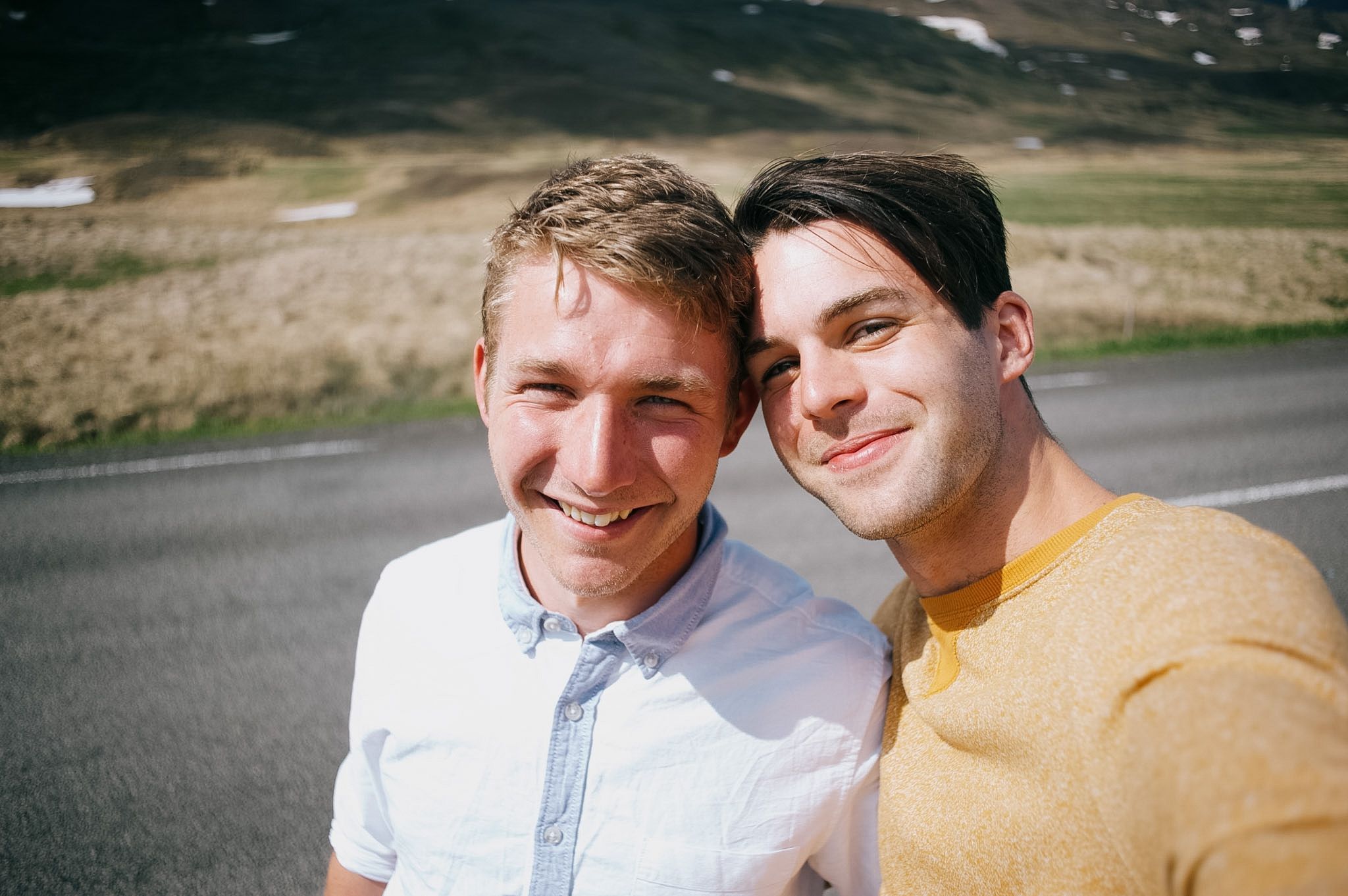 Two men squashed into a self-portrait at the roadside, both squinting into the sun